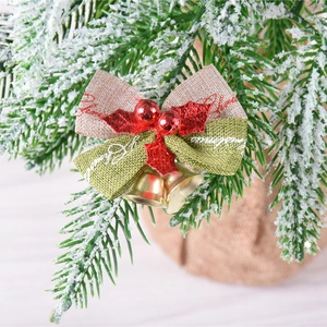 Christmas linen bow with golden bell and red berries hanging on frosted pine branch