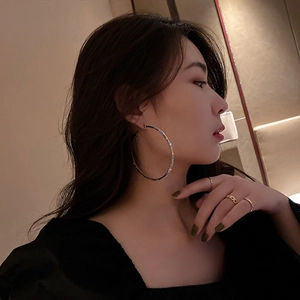 Close-up of oversized silver hoop earrings with sparkling crystals on a female model