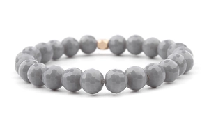 Detail view of grey faceted glass beads with a central golden hexagonal metal accent