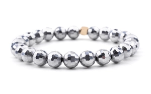 Macro detail of faceted silver round beads and a gold cube accent on a stretch bracelet