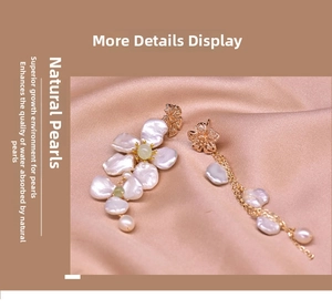 Detail of asymmetrical gold earrings featuring natural baroque pearls and tassel on pink silk