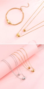 Detail of double-layer stainless steel heart necklace and matching bracelet set in gold