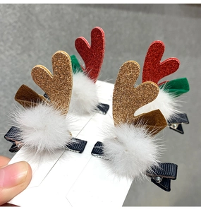 Detail of glittery red and gold reindeer antler hair clips with white pom poms and green leaves