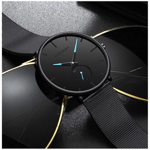 Close-up of black mesh strap watch with blue hands resting on stylish sunglasses