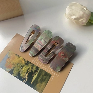 Detailed close-up of iridescent acrylic hair clip set with marble textures on a postcard