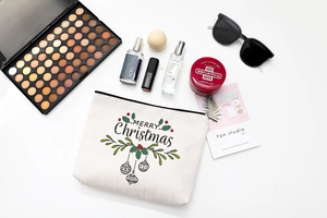 Flat lay of Christmas canvas makeup bag with Merry Christmas print and festive accessories