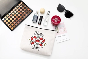 Flat lay of Holly Jolly Christmas makeup bag with cosmetics on a white background