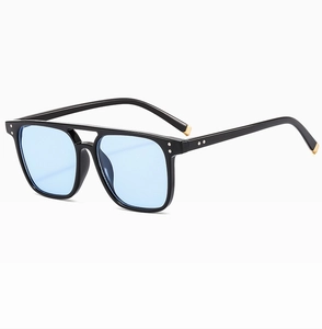 Detail of black square sunglasses with light blue lenses and silver rivet accents