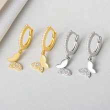 Detail of butterfly drop earrings in gold and silver finish with sparkling zircons