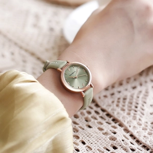 Close-up of a minimalist green leather strap watch on a woman's wrist with rose gold case