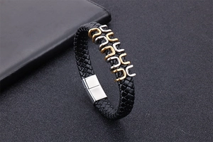 Macro view of men's braided black leather bracelet with gold and silver U-links