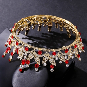 Detailed view of luxury gold leaf bridal crown with red crystals on black stand