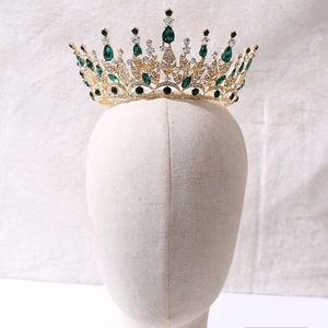Detail of a golden leaf tiara with green and clear rhinestones on a model's head