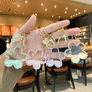 Close-up of sakura acrylic liquid quicksand keychain charms in pastel colors with golden rings