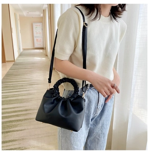 Detail of black leather handbag with unique scrunchie handle and adjustable shoulder strap