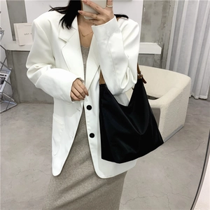 Minimalist black tote bag styled with a white blazer for a professional commute look