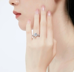 Pear cut zircon engagement ring set with silver metal band on model's hand