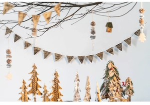 Close-up of natural birch bark bunting flags and pine cones on a rustic wooden branch