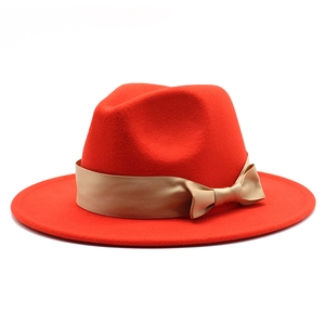 Detailed close-up of red wool felt fedora with elegant gold satin ribbon and bow accent