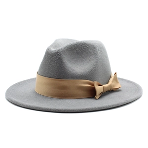 Detail shot of mid-grey wool fedora hat featuring a smooth golden ribbon bow and flat brim