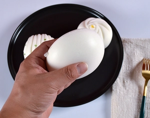 Giocattolo squishy a forma di panino al vapore premuto per mostrare la morbida texture PU