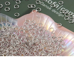Macro shot of silver open jump rings for DIY jewelry making on a shell tray