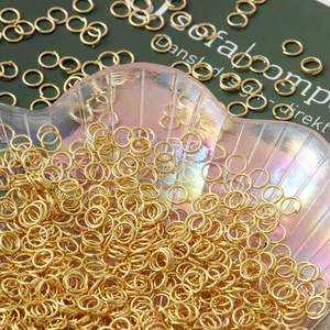 Bulk gold plated 18K brass open jump rings for jewelry making in a shell tray