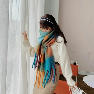 Detailed view of colorful rainbow plaid scarf texture with thick tassels and soft fabric