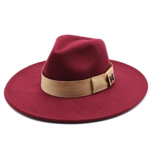 Detail of burgundy wool fedora featuring champagne satin band and black metal M charm