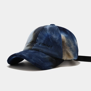 Close-up of tie-dye plush baseball cap with Winter Comes embroidery and fuzzy texture
