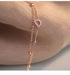 Detailed macro view of a rose gold double-layered bracelet with a pavé D-letter pendant