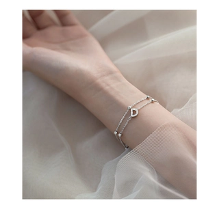 Close-up of a layered S925 silver bracelet featuring a sparkling crystal D charm