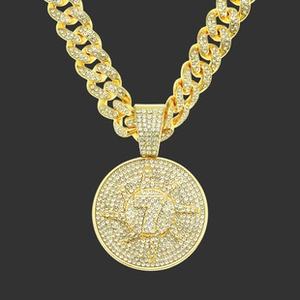 Detail of gold iced out Cuban link chain with a round number 7 goat pendant necklace