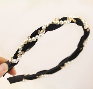 Detail showing hand-held wavy black fabric headband with faux pearls and rhinestones