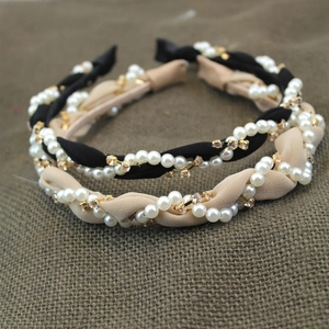 Detail of twisted fabric headband with pearls and gold rhinestones in black and beige