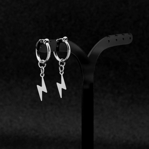 Macro detail of silver stainless steel lightning bolt pendant earrings on black stand
