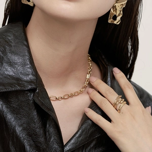 Model wearing a gold bold chain choker necklace with ripple rings and earrings jewelry set