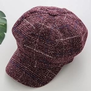 Detailed close-up of dark wine red plaid tweed texture on a stylish newsboy octagonal hat