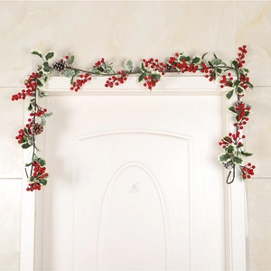 Guirlande de Noël avec pommes de pin et baies rouges fixée sur un cadre de porte blanc