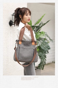 Detail of grey canvas tote bag featuring brown handles and detachable shoulder strap