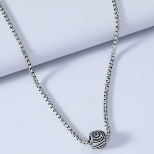 Close-up of silver stainless steel cylinder pendant with spiral texture on box chain