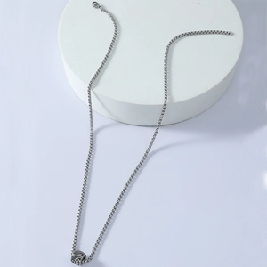 Detailed close-up of a silver stainless steel cube pendant on a box chain for men