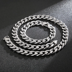 Detailed view of silver polished stainless steel Cuban link chain on black texture