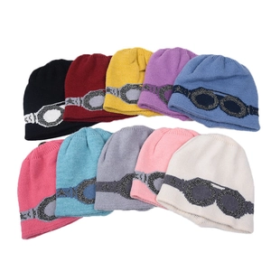 Detailed grid of knitted beanies in ten colors featuring a creative goggles knit pattern