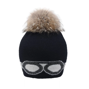 Détail du bonnet en tricot noir avec motif de lunettes et pompon en fourrure moelleux