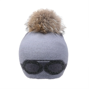 Détail du bonnet en maille grise avec motif lunettes à paillettes et pompon en fourrure