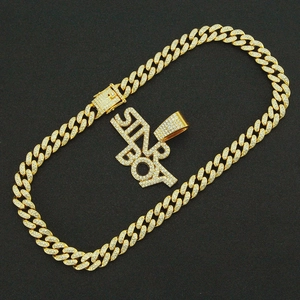 Macro detail of gold plated iced out Star Boy pendant on crystal encrusted Cuban chain