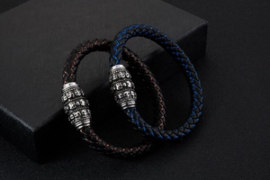 Detail of woven leather bracelets with skull metal charms on a dark textured gift box