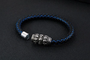 Close-up of skull magnetic clasp on black braided leather bracelet with blue stitching