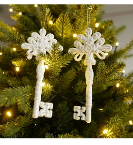 Close-up of white glitter key-shaped Christmas ornaments hanging on a festive tree branch